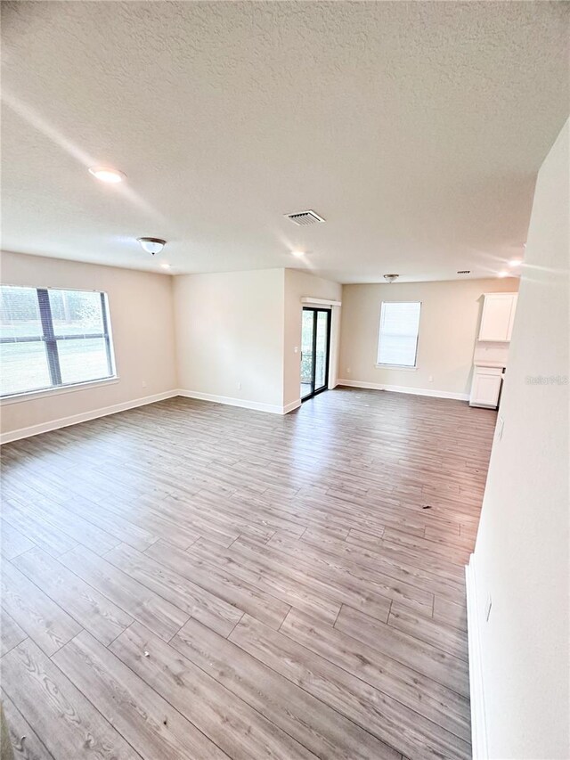 empty room with light hardwood / wood-style flooring and a textured ceiling