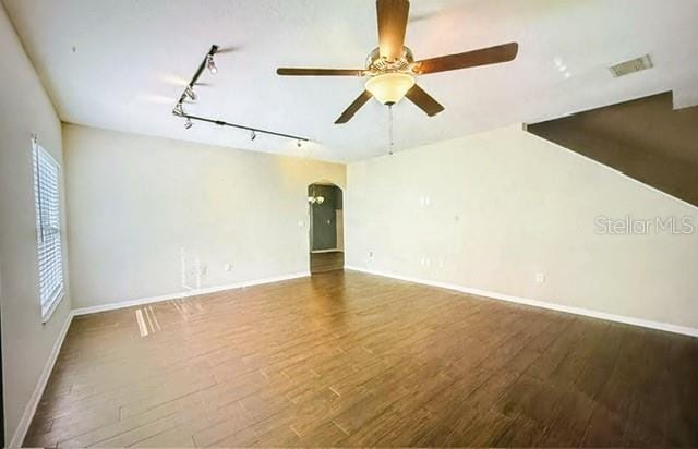 empty room featuring ceiling fan, wood-type flooring, plenty of natural light, and track lighting