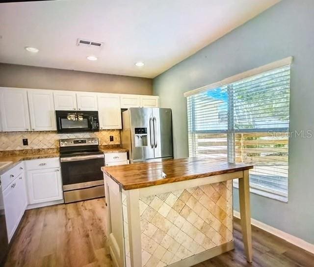 kitchen featuring appliances with stainless steel finishes, white cabinetry, tasteful backsplash, hardwood / wood-style flooring, and butcher block countertops