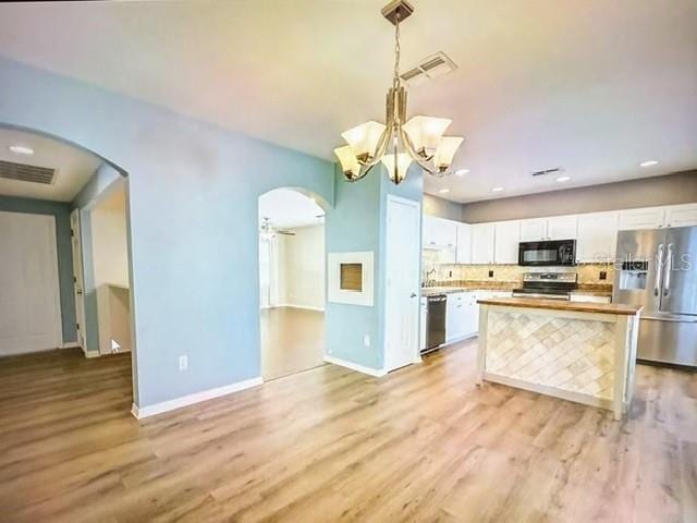 kitchen featuring pendant lighting, appliances with stainless steel finishes, a kitchen island, white cabinetry, and light hardwood / wood-style floors