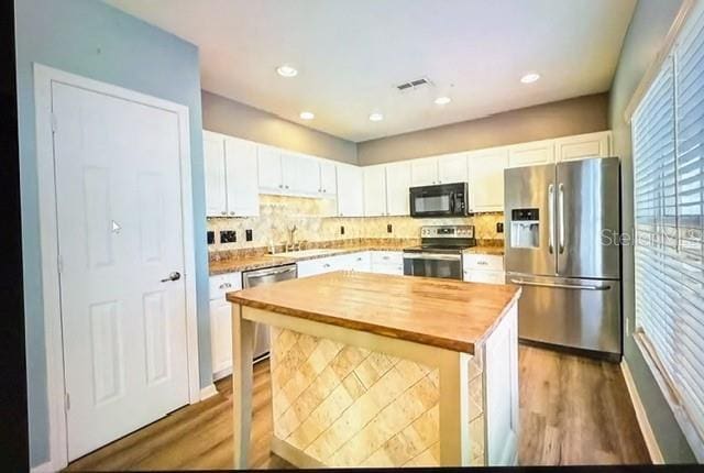 kitchen featuring wooden counters, a center island, white cabinetry, stainless steel appliances, and dark hardwood / wood-style flooring