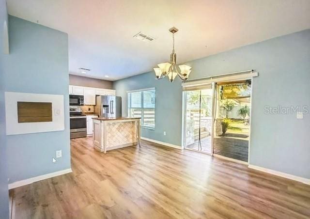 kitchen with decorative light fixtures, white cabinetry, light hardwood / wood-style flooring, appliances with stainless steel finishes, and a chandelier