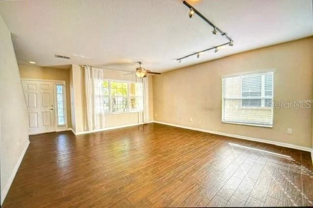 unfurnished room with ceiling fan, rail lighting, dark hardwood / wood-style flooring, and a healthy amount of sunlight