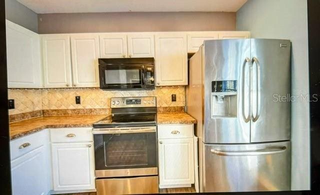 kitchen featuring tasteful backsplash, appliances with stainless steel finishes, dark stone countertops, and white cabinetry