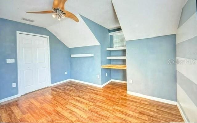 bonus room featuring ceiling fan, light hardwood / wood-style floors, built in shelves, and lofted ceiling