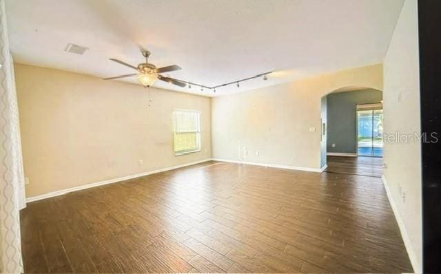 unfurnished room featuring dark wood-type flooring, track lighting, and ceiling fan