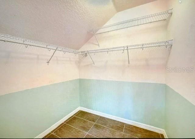 walk in closet featuring lofted ceiling and dark tile patterned flooring