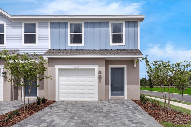 3326 Thicket St, Tavares, FL 32778 - view of property featuring board and batten siding, an attached garage, decorative driveway, and roof with shingles