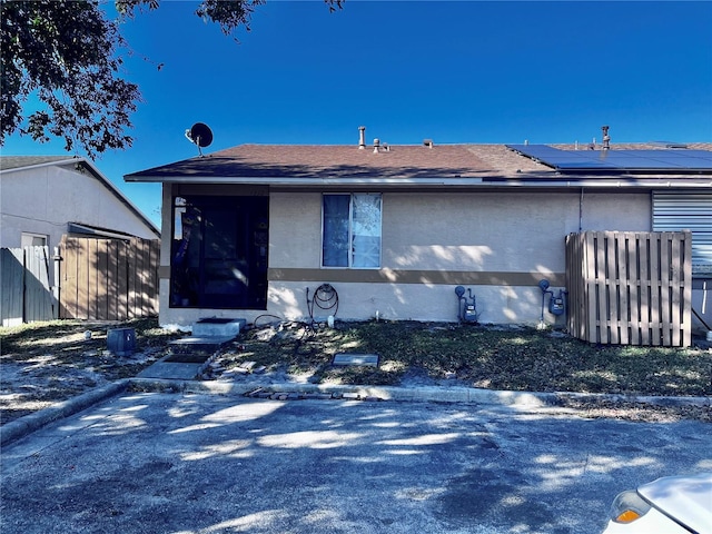 view of front of property featuring a shingled roof, fence, and stucco siding