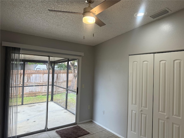 doorway to outside with light tile patterned floors, baseboards, visible vents, ceiling fan, and a textured ceiling