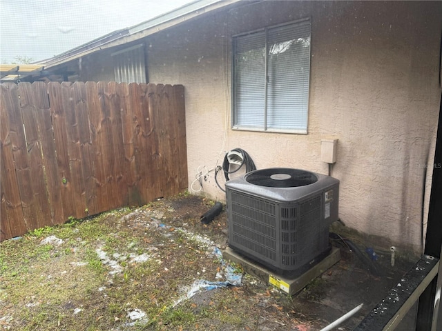 exterior details with cooling unit, fence, and stucco siding