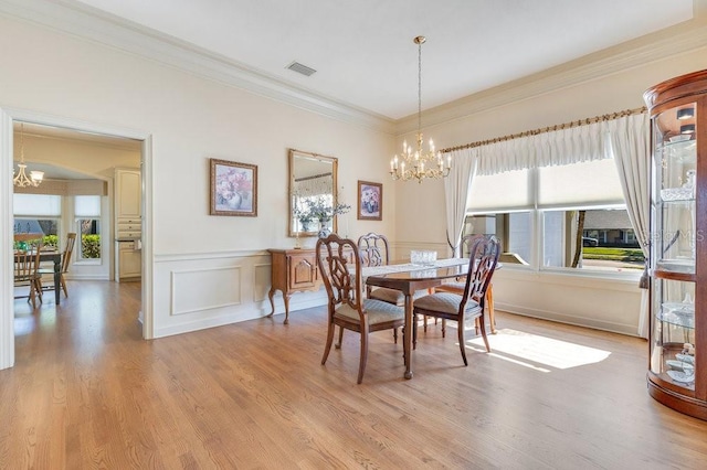 dining room with ornamental molding, light hardwood / wood-style floors, and a notable chandelier