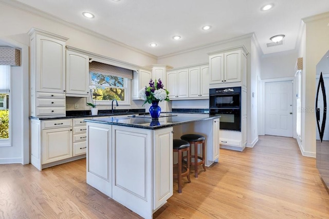 kitchen featuring light hardwood / wood-style flooring, sink, white cabinetry, and a kitchen island