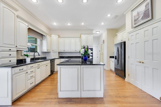 kitchen with light hardwood / wood-style floors, white cabinetry, black appliances, and a kitchen island