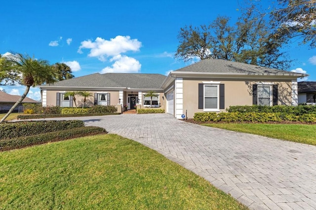 view of front of home featuring a garage, decorative driveway, a front lawn, and stucco siding