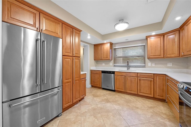 kitchen featuring sink, a raised ceiling, light tile patterned floors, and appliances with stainless steel finishes