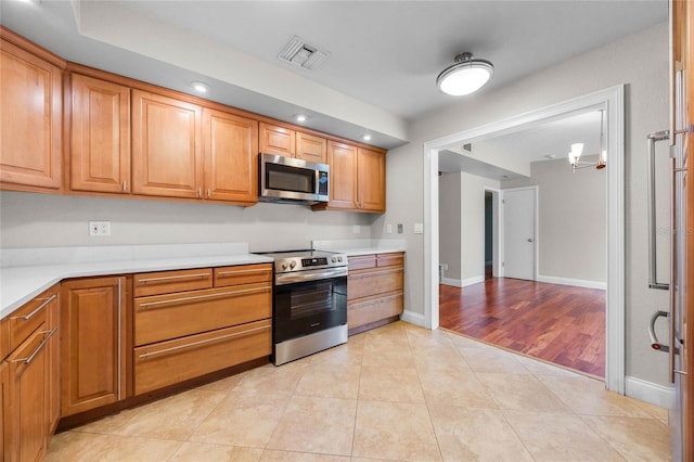 kitchen featuring appliances with stainless steel finishes, light tile patterned floors, and a chandelier