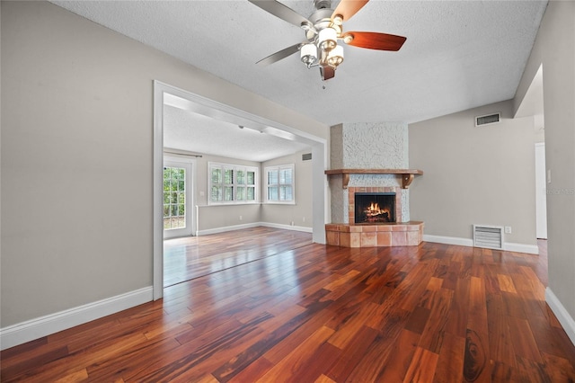 unfurnished living room featuring a fireplace, a textured ceiling, ceiling fan, and hardwood / wood-style flooring