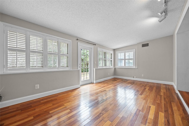 unfurnished room featuring wood-type flooring and a textured ceiling