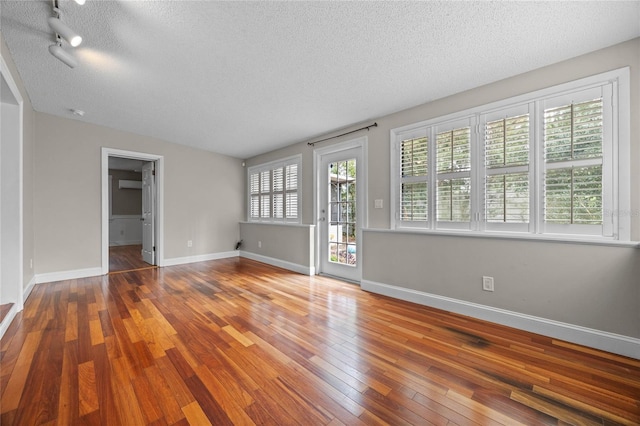 unfurnished room featuring a textured ceiling, a healthy amount of sunlight, and hardwood / wood-style flooring