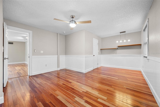 empty room featuring a textured ceiling, ceiling fan, and hardwood / wood-style floors