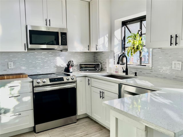 kitchen featuring light stone countertops, sink, white cabinets, and appliances with stainless steel finishes