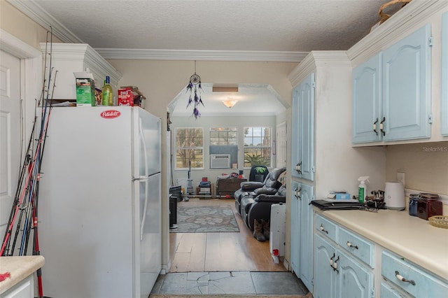 kitchen with a textured ceiling, white refrigerator, crown molding, and light hardwood / wood-style flooring