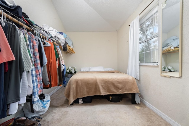 bedroom with a textured ceiling, carpet flooring, and lofted ceiling