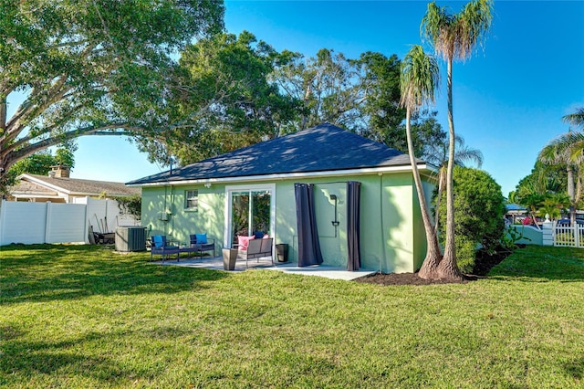 rear view of property featuring central air condition unit, a yard, and an outdoor structure