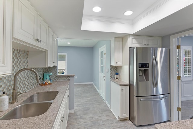 kitchen with crown molding, sink, stainless steel refrigerator with ice dispenser, tasteful backsplash, and white cabinetry