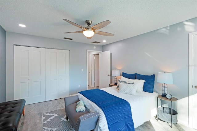 bedroom featuring ceiling fan, light wood-type flooring, a textured ceiling, and a closet