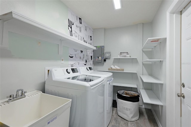 laundry room featuring washer and clothes dryer, light wood-type flooring, sink, and electric panel