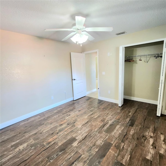 unfurnished bedroom with ceiling fan, dark hardwood / wood-style floors, a textured ceiling, and a closet