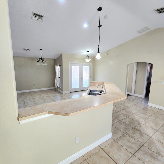 kitchen with pendant lighting, sink, light tile patterned floors, vaulted ceiling, and french doors