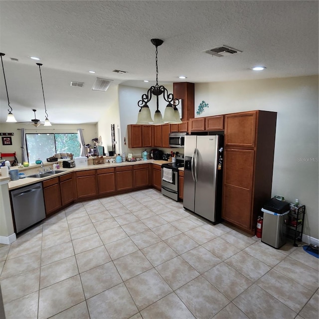 kitchen featuring sink, an inviting chandelier, hanging light fixtures, a textured ceiling, and stainless steel appliances