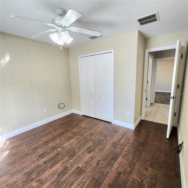 unfurnished bedroom featuring ceiling fan, a closet, dark hardwood / wood-style flooring, and a textured ceiling