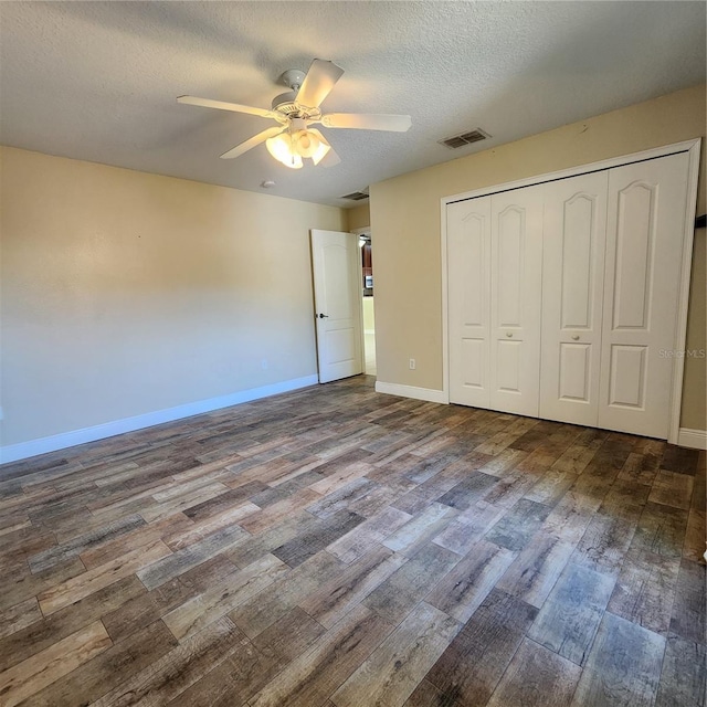 unfurnished bedroom with ceiling fan, wood-type flooring, a closet, and a textured ceiling