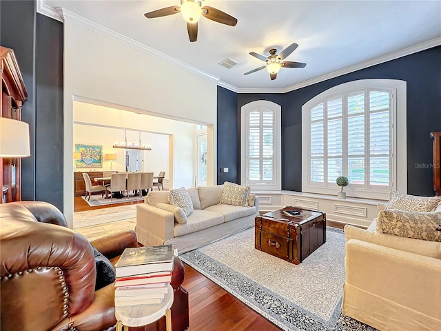 living room featuring hardwood / wood-style floors, ceiling fan with notable chandelier, and ornamental molding