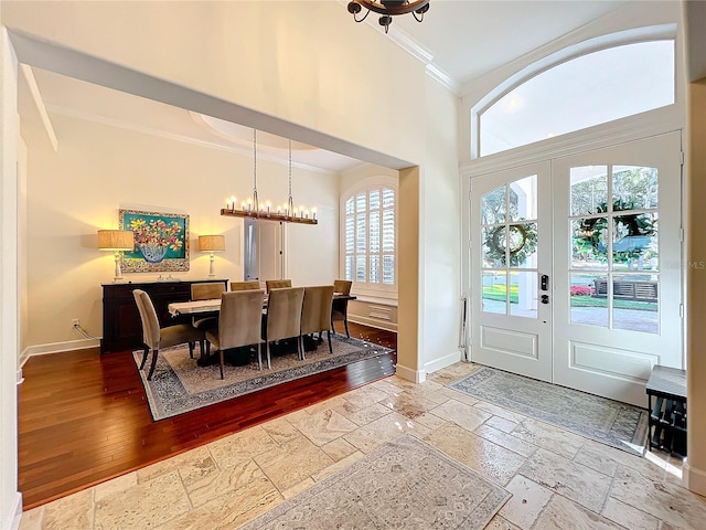 entryway featuring french doors, crown molding, and a notable chandelier