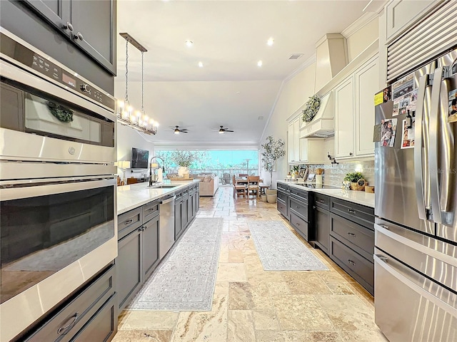 kitchen featuring sink, hanging light fixtures, stainless steel appliances, white cabinets, and ceiling fan with notable chandelier