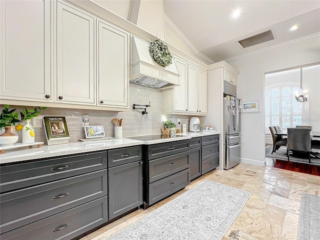 kitchen with white cabinetry, tasteful backsplash, premium range hood, stainless steel fridge, and black electric cooktop