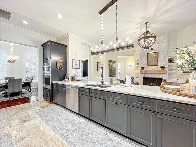 kitchen featuring a fireplace, appliances with stainless steel finishes, pendant lighting, and gray cabinetry