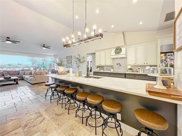 kitchen with a breakfast bar, ceiling fan with notable chandelier, decorative light fixtures, and vaulted ceiling