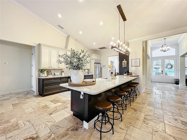 kitchen featuring sink, hanging light fixtures, high vaulted ceiling, a notable chandelier, and a kitchen bar