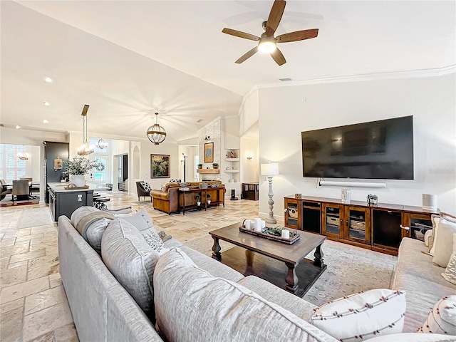 living room featuring ceiling fan with notable chandelier, built in features, ornamental molding, and vaulted ceiling