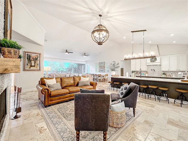 living room with ceiling fan with notable chandelier, sink, lofted ceiling, and a fireplace