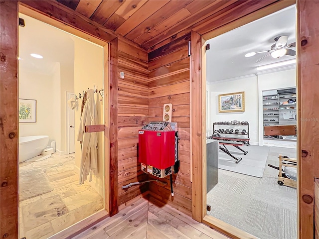 bathroom featuring ceiling fan, wood walls, wood ceiling, and a tub