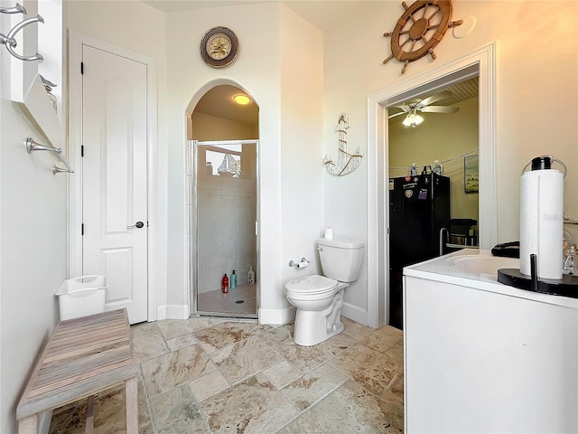 bathroom with vanity, a shower with door, toilet, and ceiling fan