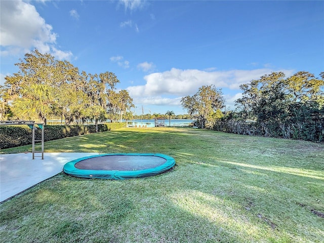 view of yard featuring a water view and a trampoline