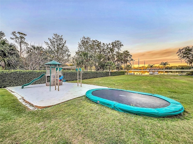 playground at dusk with a lawn and a trampoline